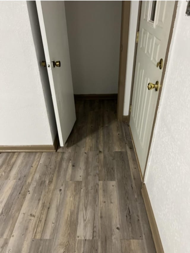 corridor with wood finished floors and baseboards