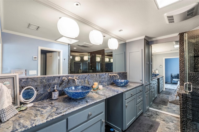 full bath featuring stone finish floor, crown molding, and a sink