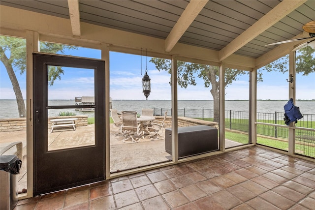 unfurnished sunroom featuring lofted ceiling with beams and a water view