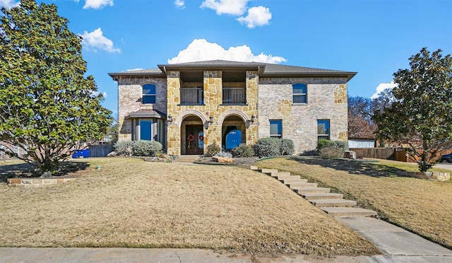 view of front of property with a balcony, a front lawn, and fence