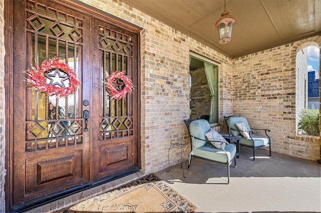 property entrance with a porch and brick siding