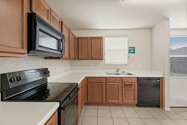 kitchen featuring a sink, brown cabinets, black appliances, and light tile patterned floors