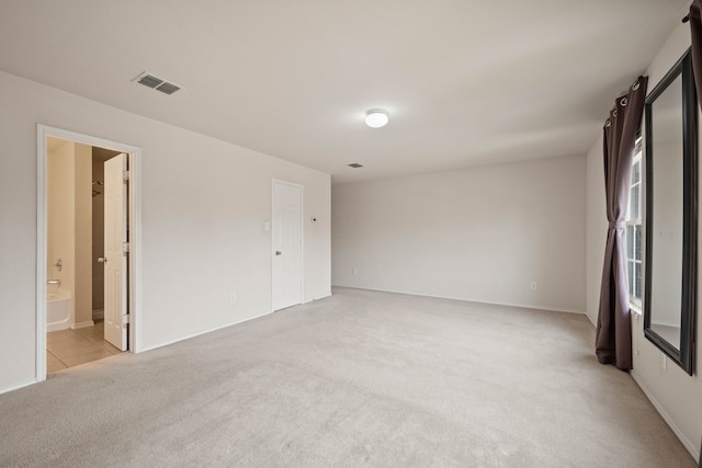 spare room featuring visible vents and light colored carpet