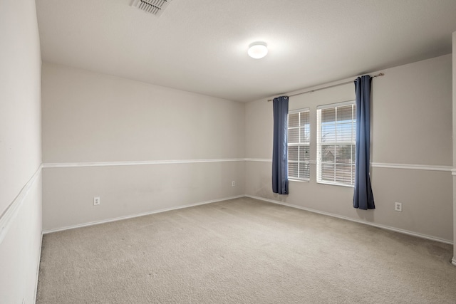 spare room featuring baseboards, visible vents, and carpet floors