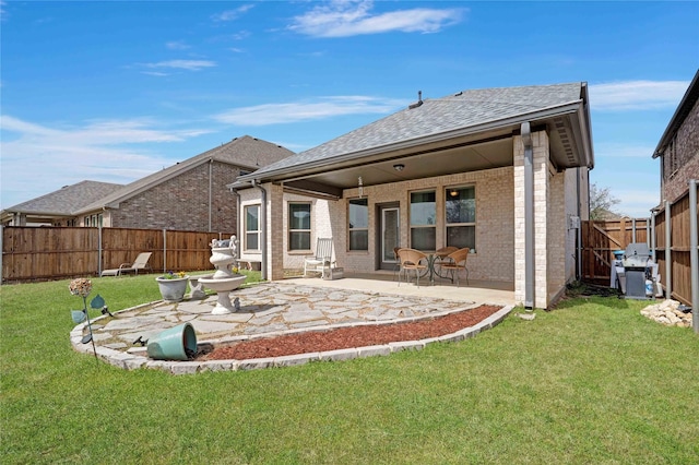 rear view of house with a yard, brick siding, a fenced backyard, and a patio area