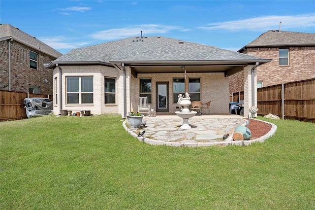 rear view of property featuring a patio, roof with shingles, a lawn, fence private yard, and brick siding