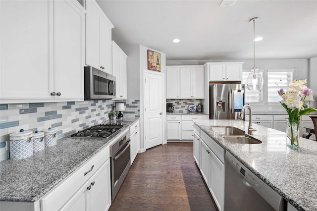 kitchen with a sink, dark wood finished floors, stainless steel appliances, white cabinets, and decorative backsplash