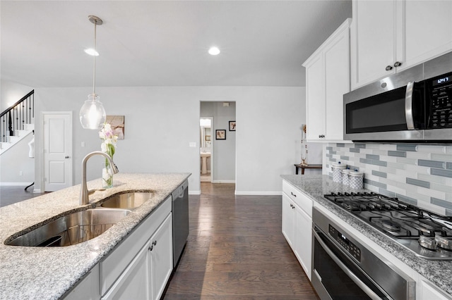 kitchen with dark wood-type flooring, a sink, white cabinetry, stainless steel appliances, and decorative backsplash