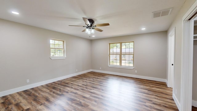 unfurnished room featuring visible vents, a healthy amount of sunlight, baseboards, and wood finished floors