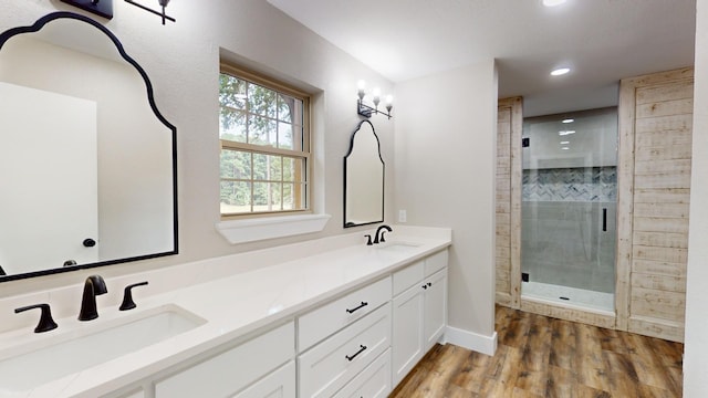 full bath featuring double vanity, a stall shower, wood finished floors, and a sink