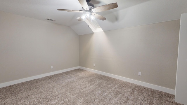 carpeted spare room featuring visible vents, a ceiling fan, baseboards, and vaulted ceiling