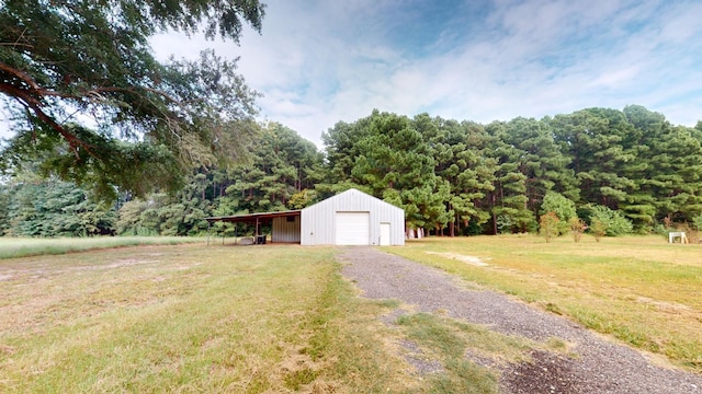 view of yard with a detached garage, an outbuilding, and a view of trees