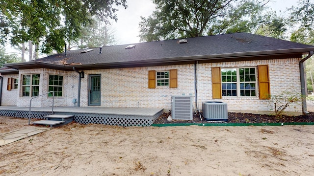 rear view of house featuring cooling unit, brick siding, a wooden deck, and a shingled roof