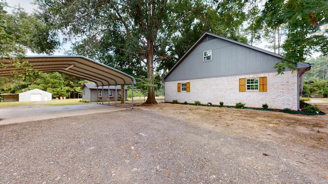 view of home's exterior featuring a detached carport, an outdoor structure, brick siding, and driveway