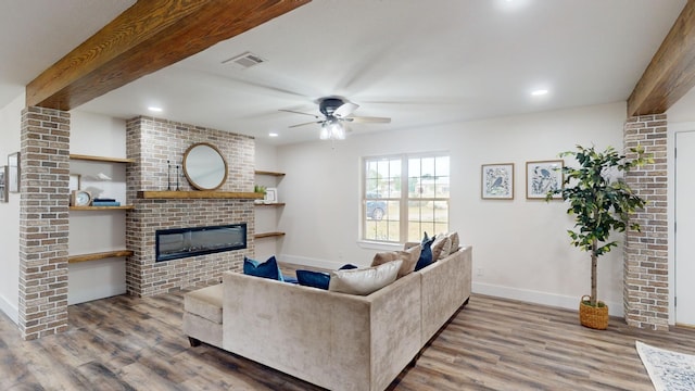 living room with beamed ceiling, a fireplace, and wood finished floors