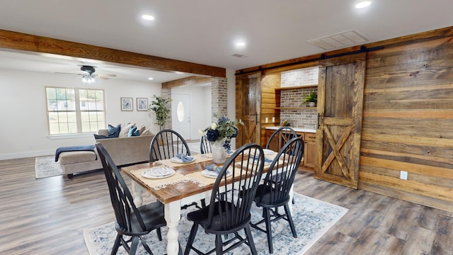 dining area with wood finished floors, visible vents, recessed lighting, a barn door, and beamed ceiling