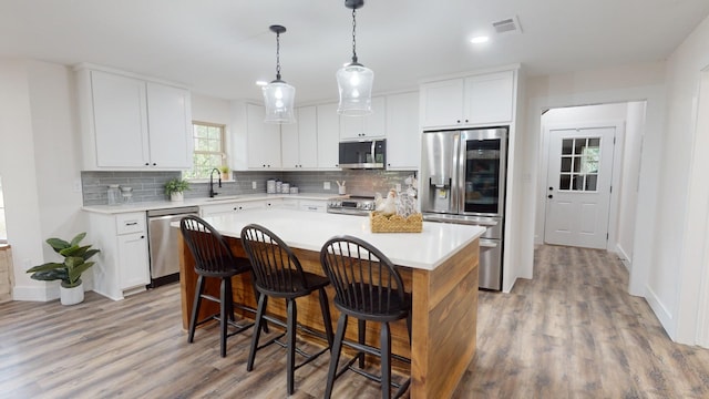 kitchen featuring visible vents, backsplash, light countertops, appliances with stainless steel finishes, and a sink