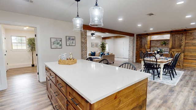 kitchen featuring light wood-style flooring, pendant lighting, brown cabinets, and a center island