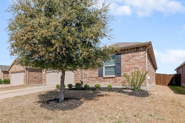 obstructed view of property featuring brick siding, fence, concrete driveway, a front yard, and an attached garage