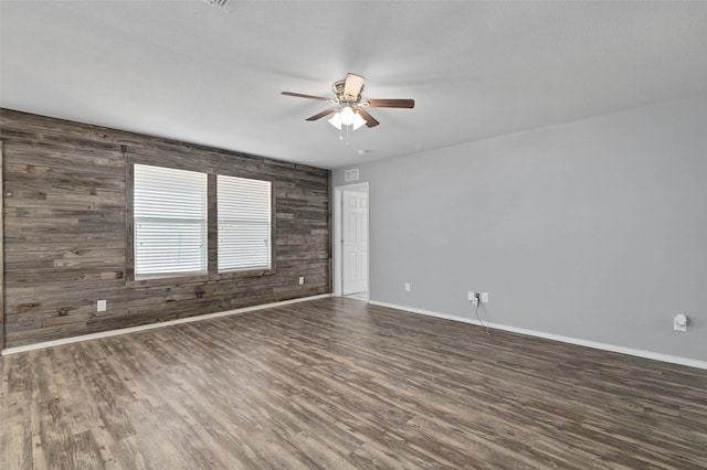 unfurnished room featuring ceiling fan, baseboards, wood finished floors, and wood walls