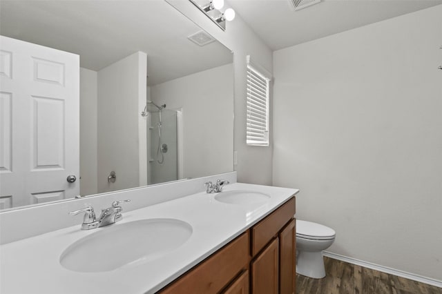 full bathroom featuring double vanity, wood finished floors, a stall shower, and a sink