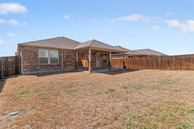 rear view of property featuring a patio area, a yard, a fenced backyard, and brick siding