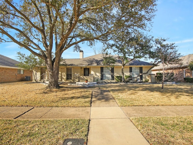 ranch-style house featuring a front yard, central air condition unit, brick siding, and a chimney