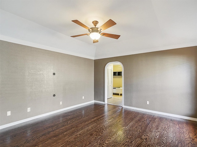 empty room featuring baseboards, wood finished floors, arched walkways, and ceiling fan