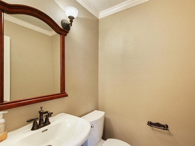 half bath with ornamental molding, toilet, and a sink