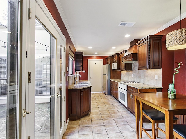 kitchen featuring ornamental molding, white appliances, premium range hood, and a sink