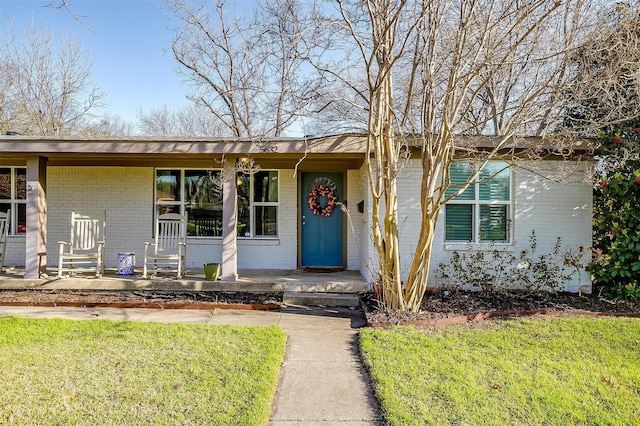 view of front of house with a porch, brick siding, and a front lawn