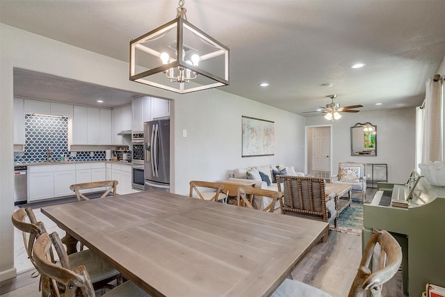 dining space featuring recessed lighting, wood finished floors, and ceiling fan with notable chandelier