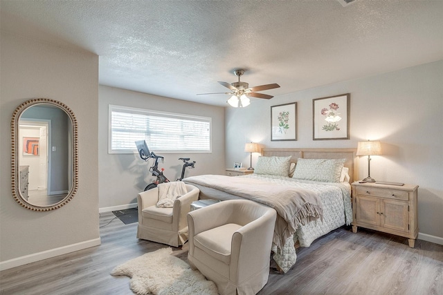 bedroom featuring baseboards, a textured ceiling, ceiling fan, and light wood finished floors