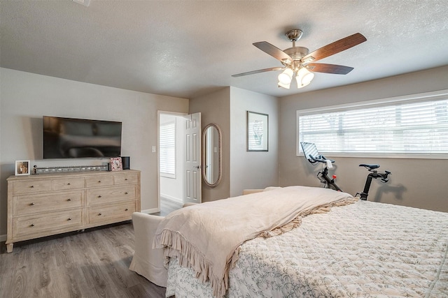 bedroom with a ceiling fan, wood finished floors, and a textured ceiling