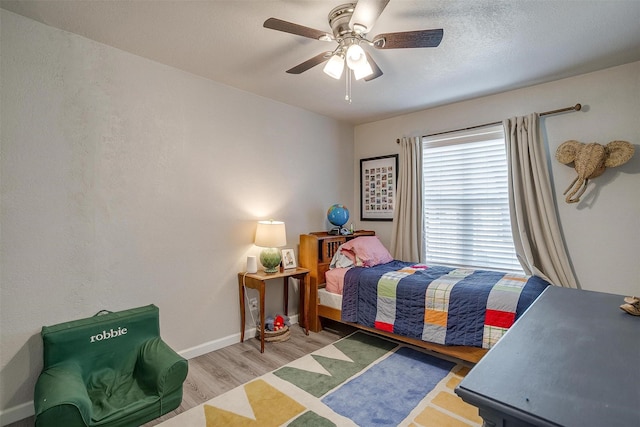 bedroom with a ceiling fan, wood finished floors, and baseboards