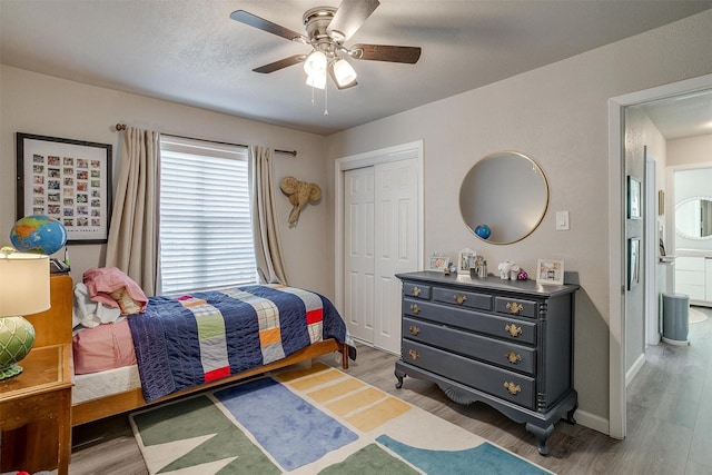 bedroom with baseboards, ceiling fan, wood finished floors, a closet, and a textured ceiling