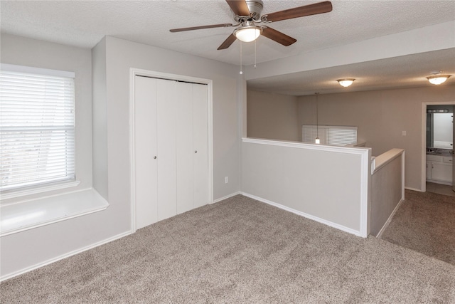 empty room featuring carpet, a ceiling fan, and a textured ceiling