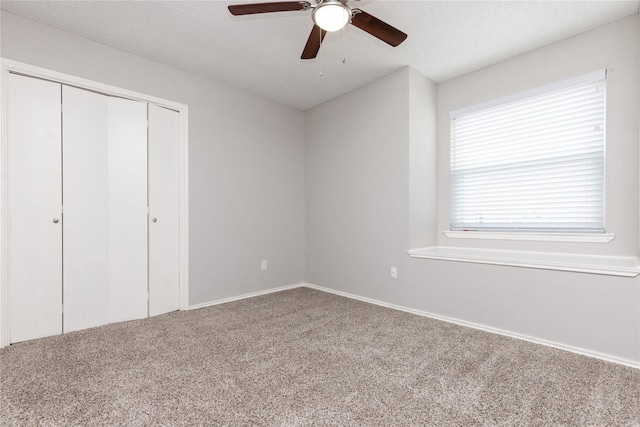 unfurnished bedroom with a closet, a textured ceiling, carpet flooring, and a ceiling fan