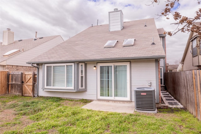 back of property with central AC, a chimney, a yard, a fenced backyard, and a gate