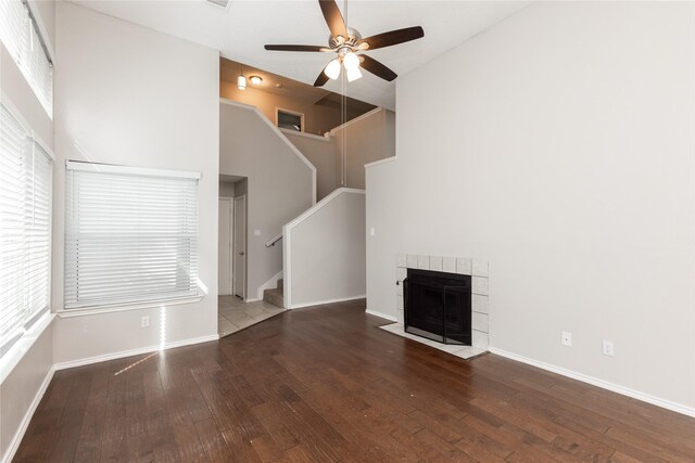 unfurnished living room featuring stairs, a fireplace, wood-type flooring, and a ceiling fan