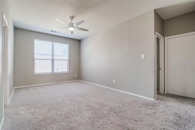 carpeted empty room with visible vents, baseboards, and a ceiling fan