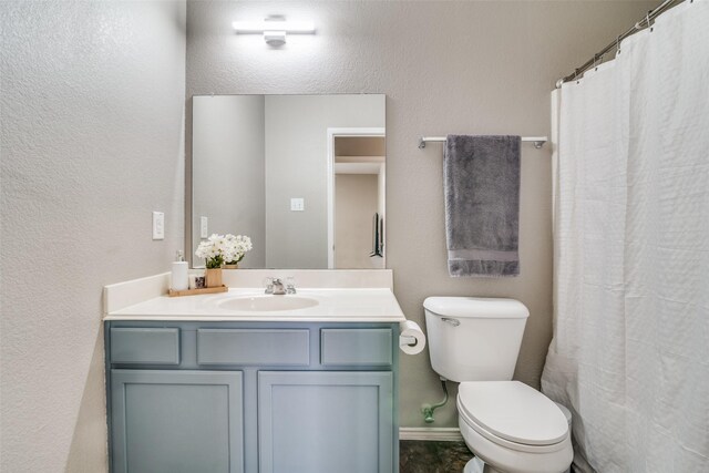 bathroom with toilet, vanity, and baseboards