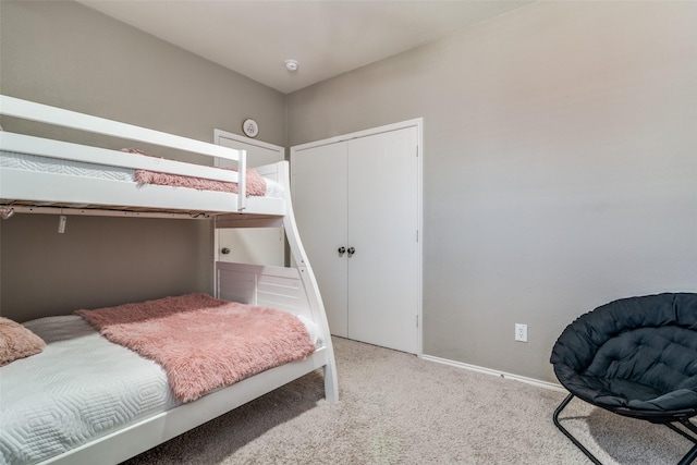 bedroom featuring a closet, light colored carpet, and baseboards