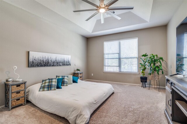 bedroom with baseboards, a raised ceiling, light carpet, and a ceiling fan