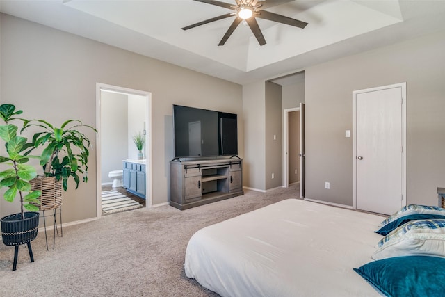 bedroom with a tray ceiling, ensuite bath, carpet floors, baseboards, and ceiling fan