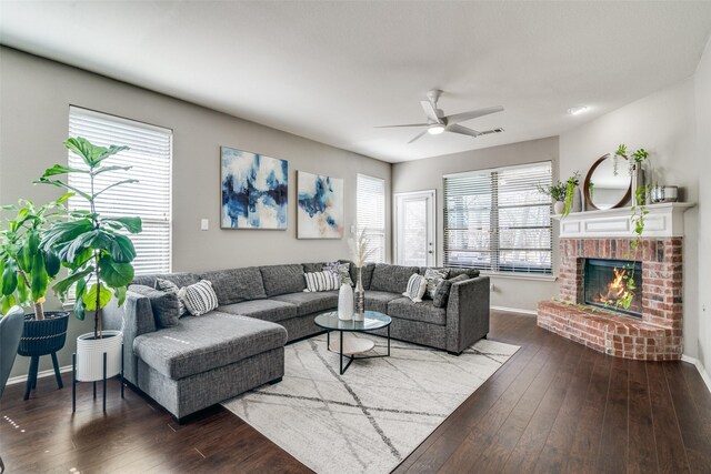 living area with a brick fireplace, baseboards, a ceiling fan, and wood-type flooring