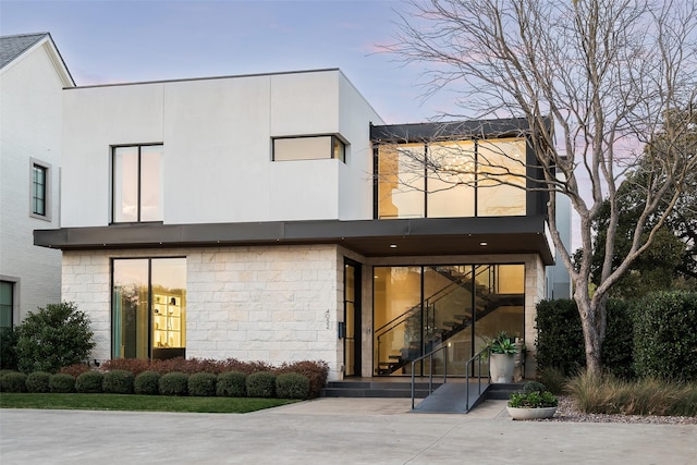 exterior space with stone siding, stucco siding, and stairway