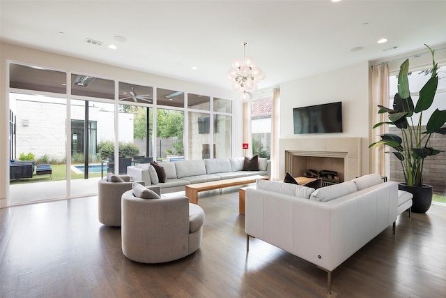 living room featuring recessed lighting, an inviting chandelier, dark wood finished floors, and a fireplace