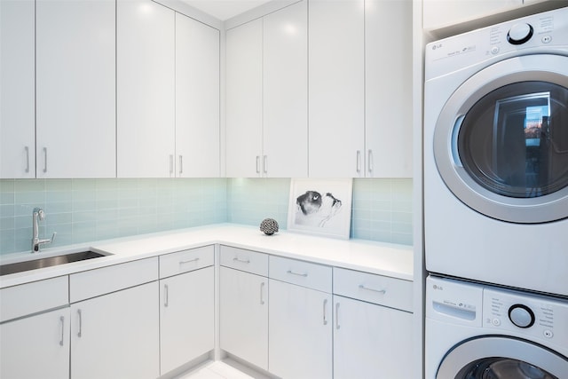 laundry area with stacked washer and dryer, cabinet space, and a sink