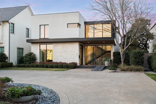 rear view of house with stone siding and stucco siding